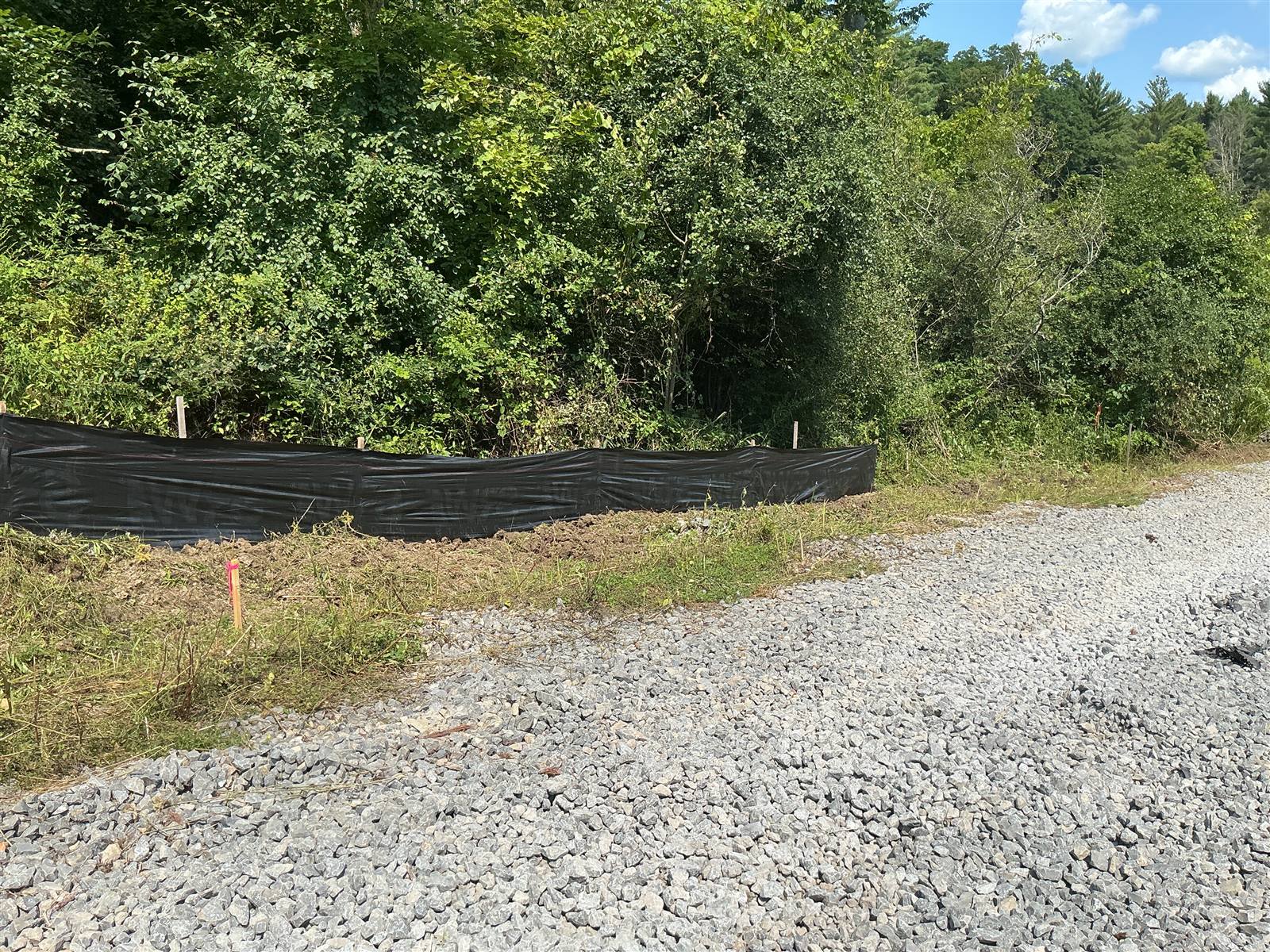 Silt fence beside a gravel access road and cut vegetation