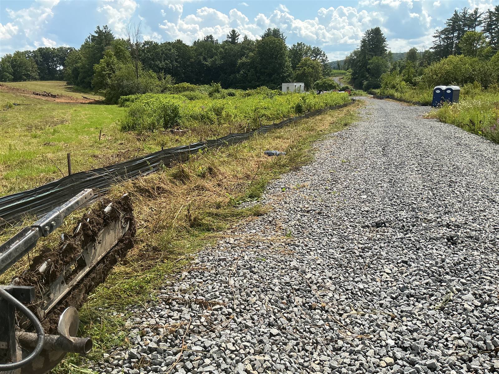 Silt fence along a gravel haul road with equipment in the foreground
