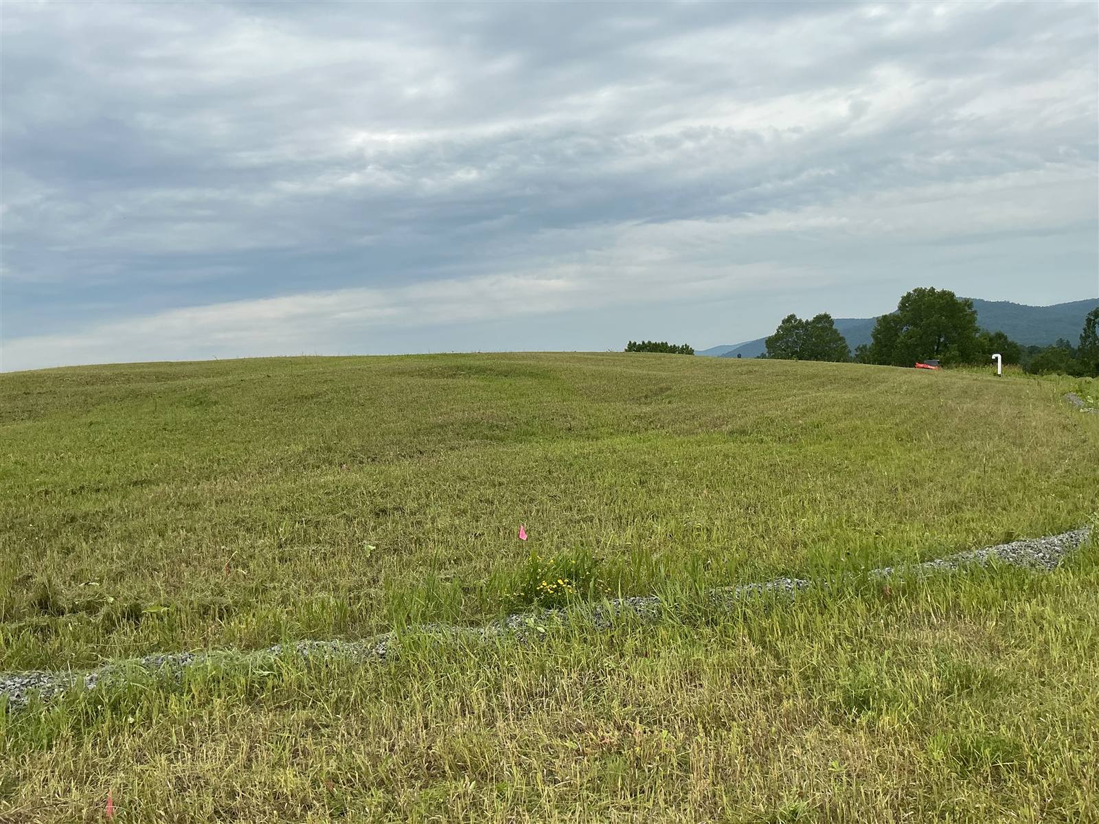 Broad mowed field under a cloudy sky