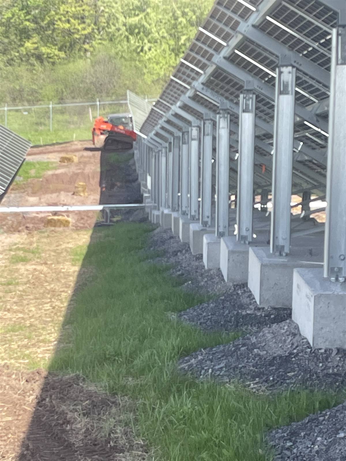 Row of solar racking piers along a seeded strip